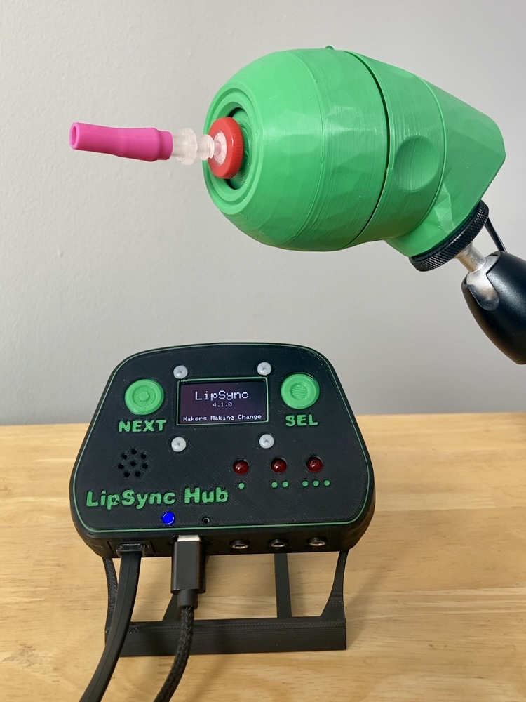 A green LipSync mouth-operated joystick beside its control hub and screen.