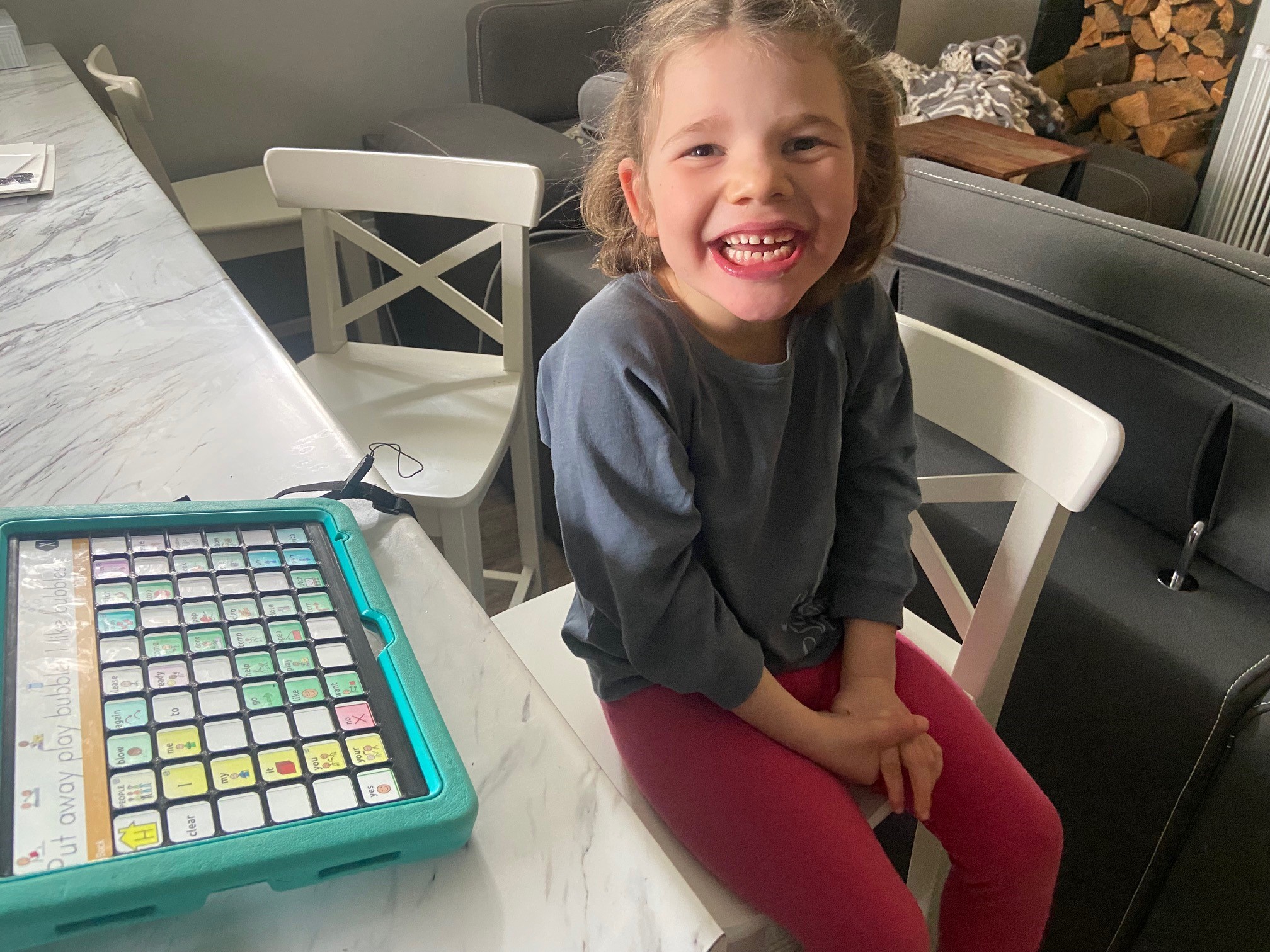 A child beside a communication tablet fitted with a grid-shaped keyguard.